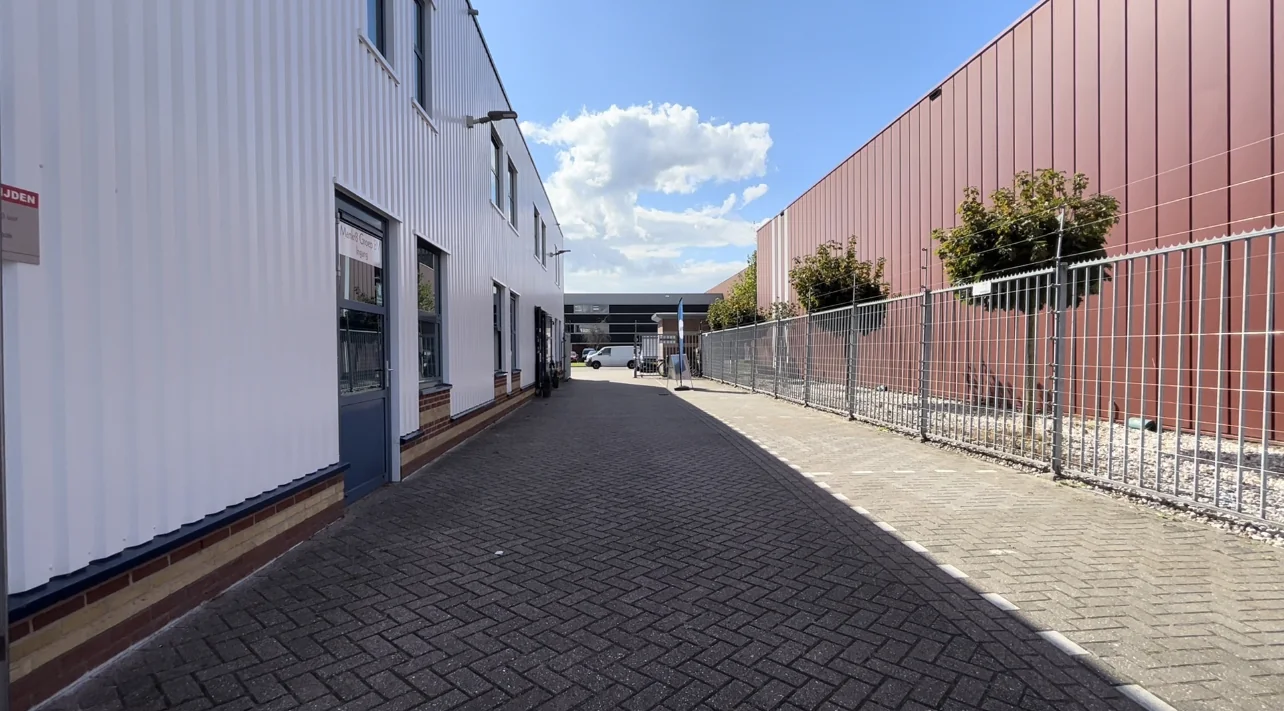 Steeg tussen twee bedrijfsgebouwen aan de Bergveste met blauw lucht en zonlicht.