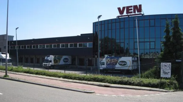 Bedrijfsgebouw van VEN aan de Weesperstraat met vrachtwagens van Sligro op het terrein.