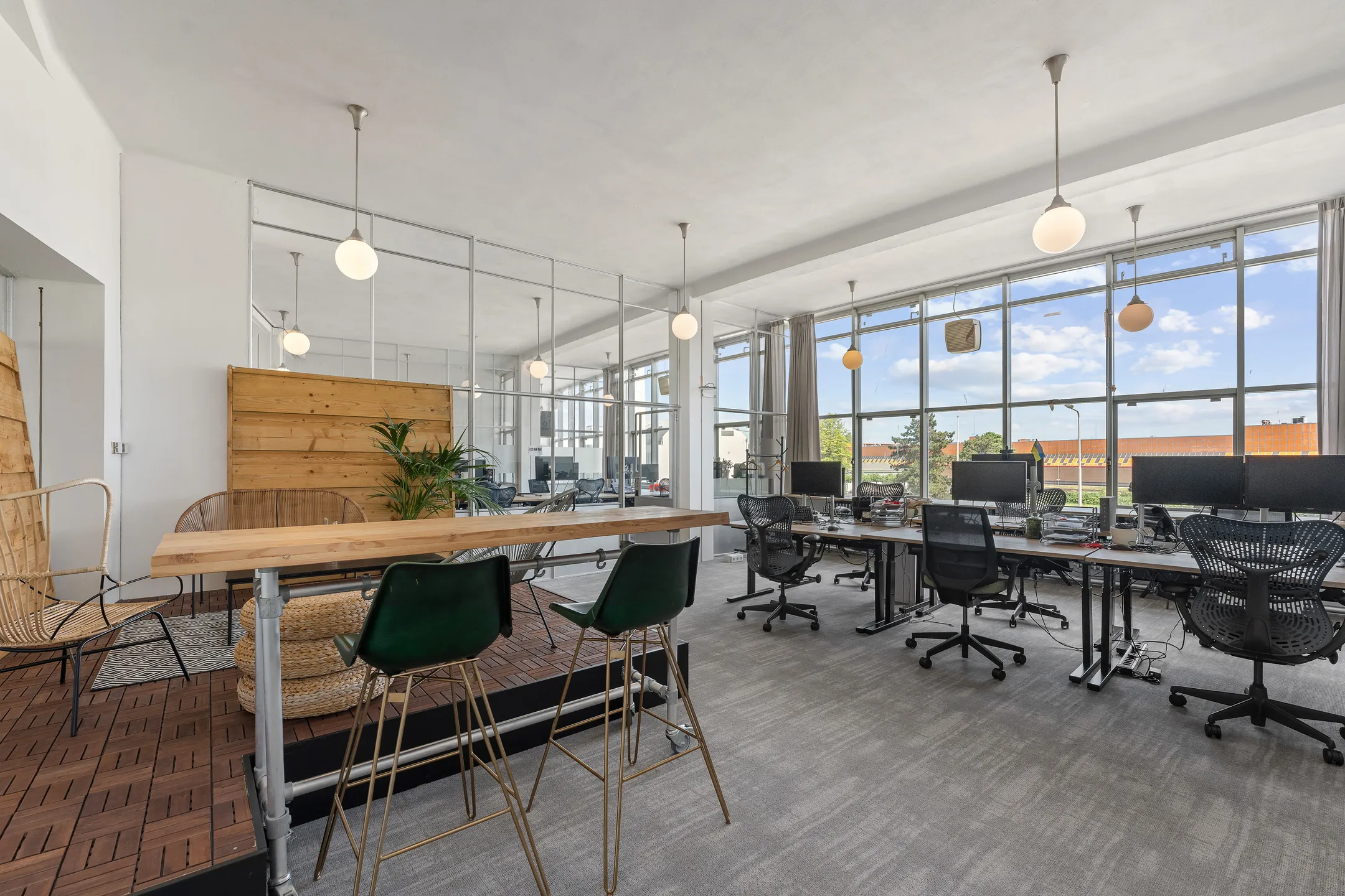 Een moderne open kantoorruimte met houten scheidingswanden, bureaus en ergonomische stoelen, verlicht door grote ramen.
