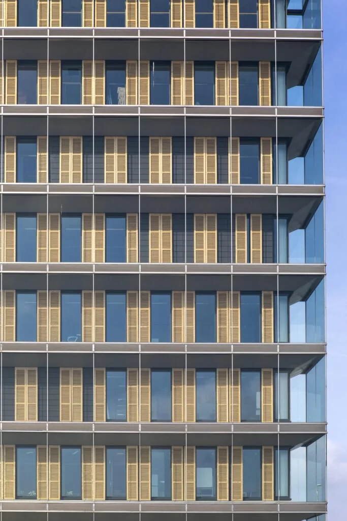 Gevel van het kantoorgebouw aan de Paasheuvelweg met glazen wanden en verticale houten lamellen.