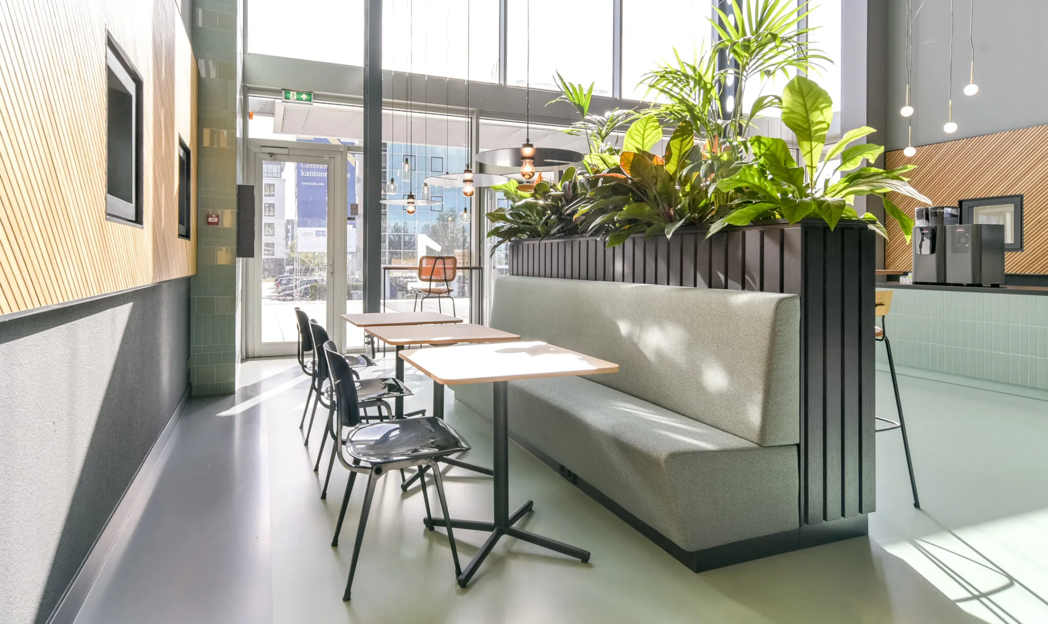 Moderne en lichte kantoorlounge aan de Paasheuvelweg met zithoeken, planten en koffiemachine.