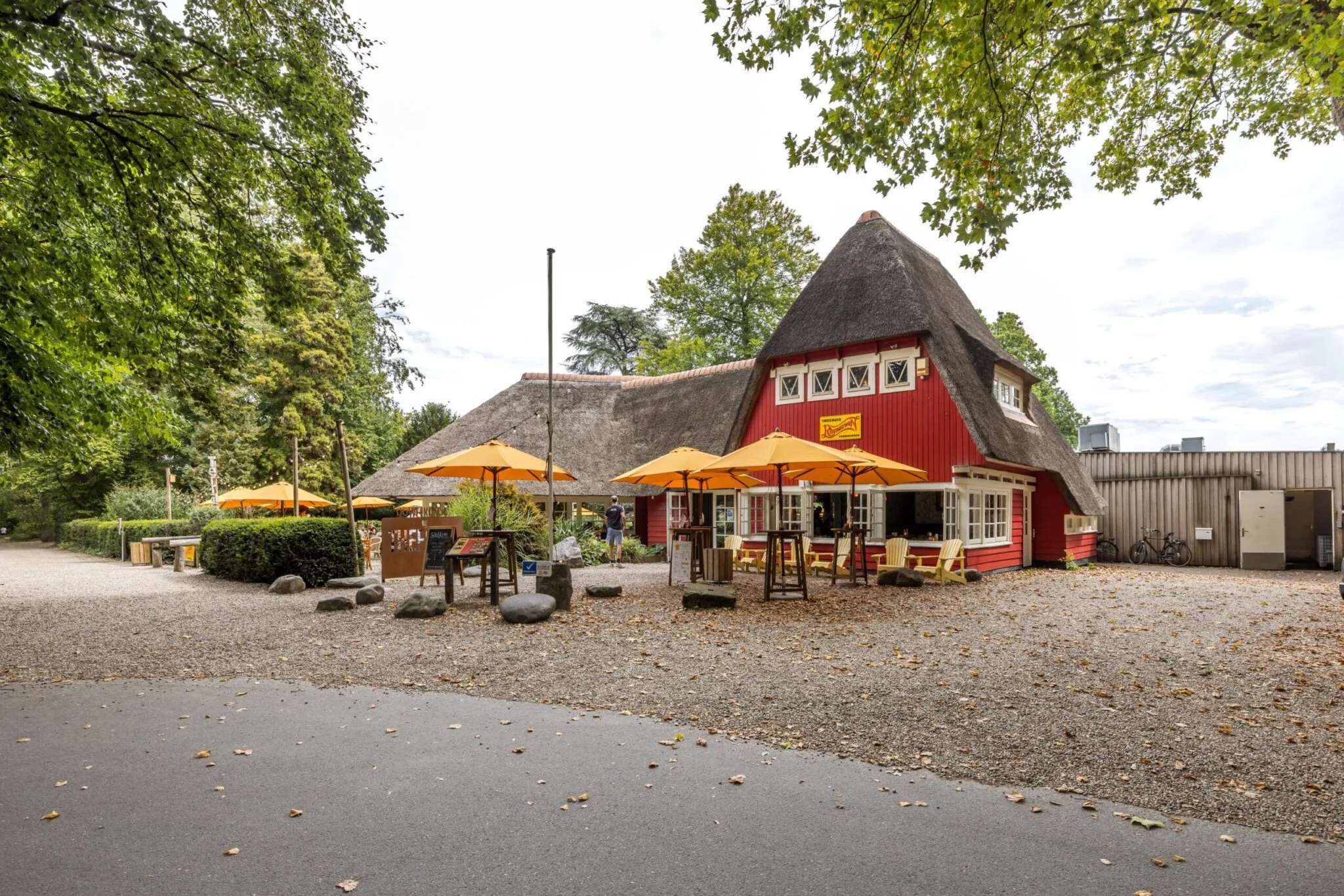 Rood gebouw met rieten dak en terras met gele parasols aan de Vossegatsedijk.