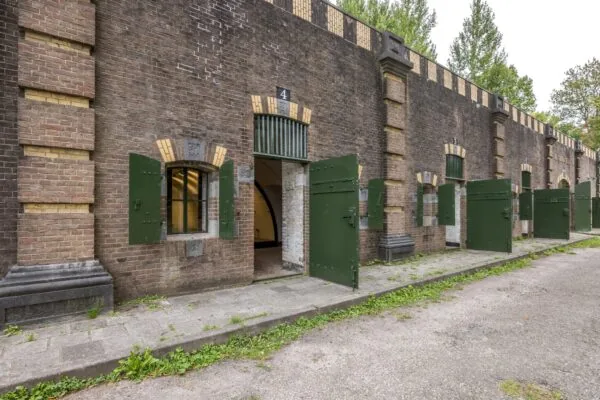 Rij van historische bakstenen fortgebouwen met groene deuren aan de Vossegatsedijk.