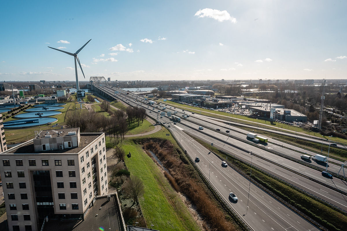 Uitzicht op het Rivium Quadrant met een snelweg, gebouwen en een windturbine op de achtergrond.