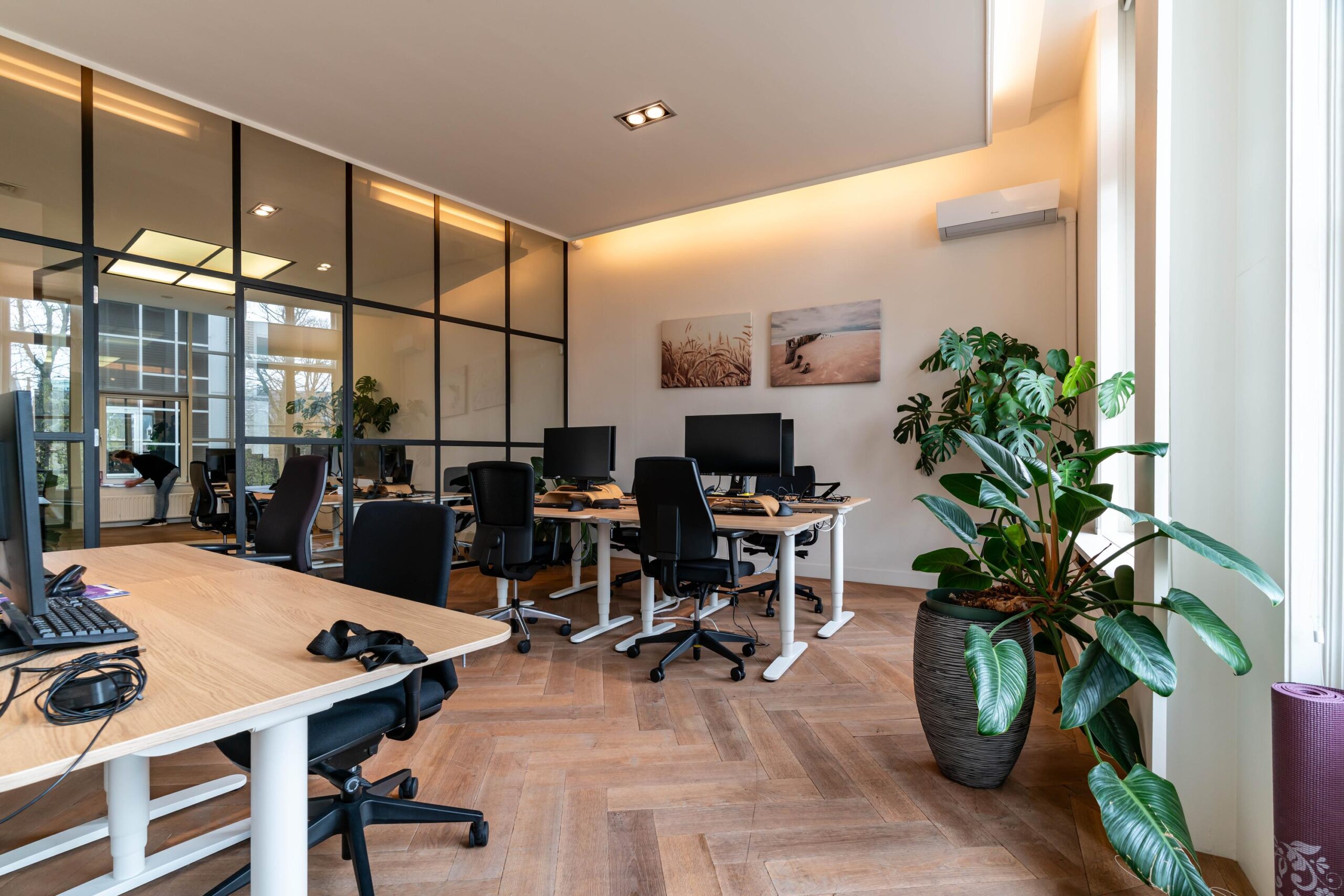 Moderne kantoorruimte aan de Lange Vijverberg met bureaus, computers, glazen wand en grote kamerplanten.
