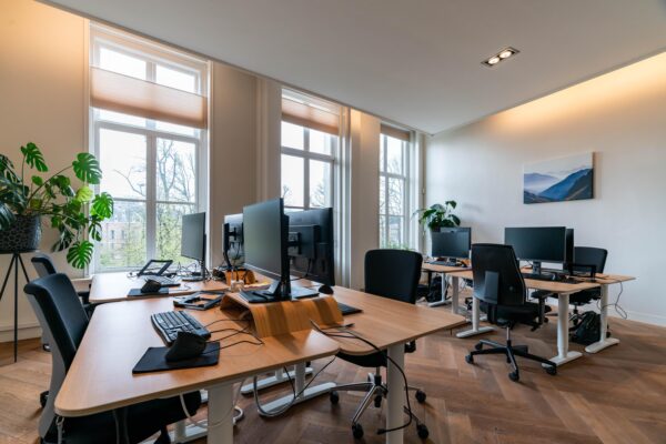 Moderne kantoorruimte aan de Lange Vijverberg met meerdere werkplekken, grote ramen en houten vloer.