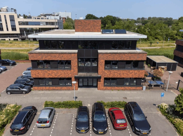 Kantoorgebouw aan de Veteranenlaan met bakstenen gevel en geparkeerde auto’s op de voorgrond.