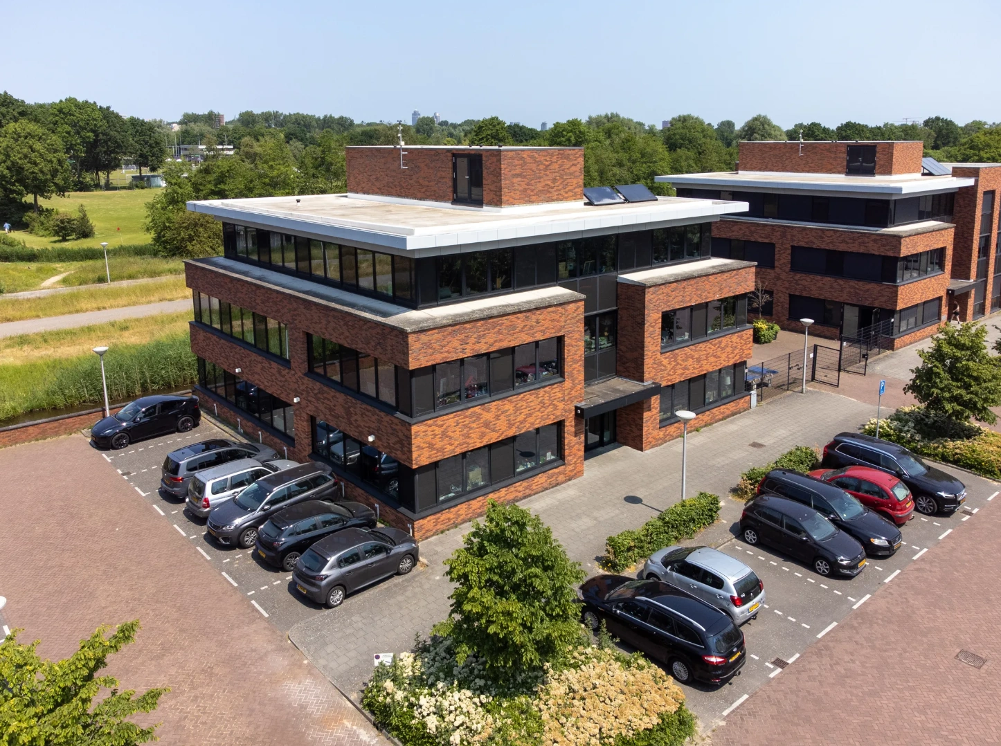 Luchtfoto van een modern kantoorpand aan de Veteranenlaan met omliggende parkeerplaatsen en groenstroken.