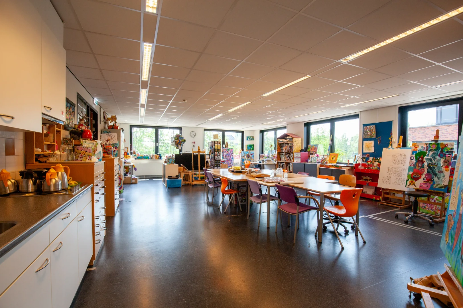 Creatieve knutselruimte in een kleurrijk klaslokaal aan de Veteranenlaan met tafels, stoelen en kunstwerken.