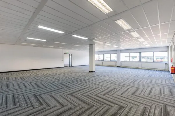 Ruime, lege kantoorruimte aan de Zonnebaan met grijs vloerpatroon en grote ramen.