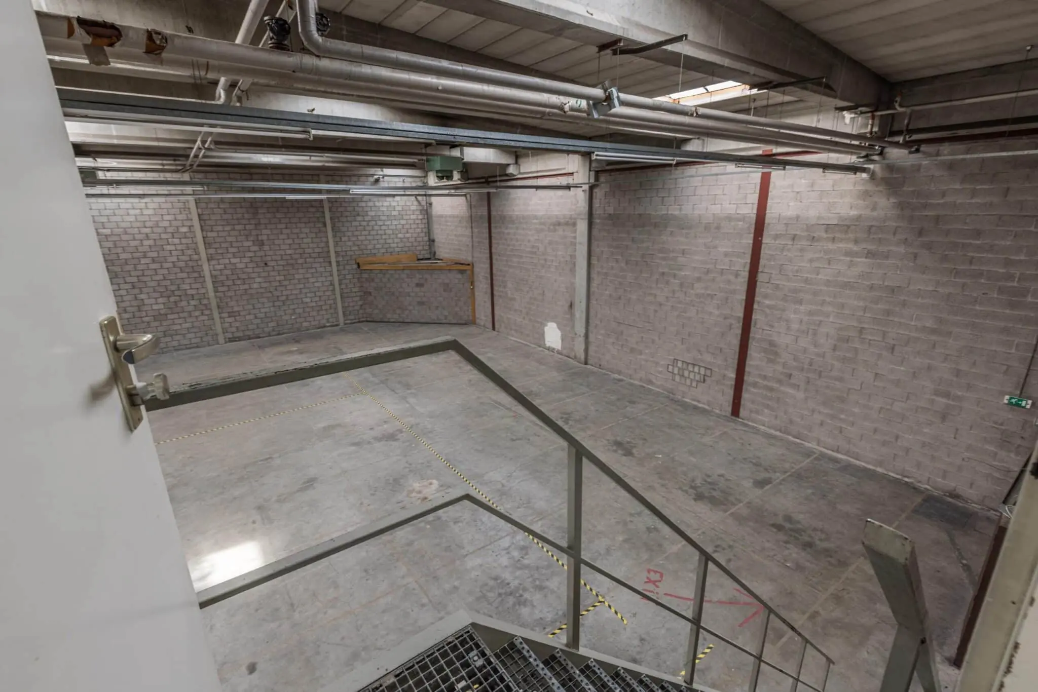 Leeg industrieel magazijn met betonnen vloeren en metalen trap aan de Zonnebaan.