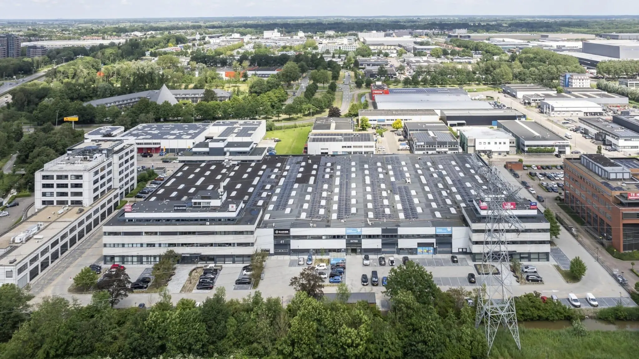 Luchtfoto van bedrijventerrein Zonnebaan in Utrecht met grote bedrijfsgebouwen voorzien van zonnepanelen.