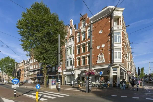 Straatbeeld van de Overtoom in Amsterdam met een hoekpand waarin eetwinkel STACH is gevestigd.