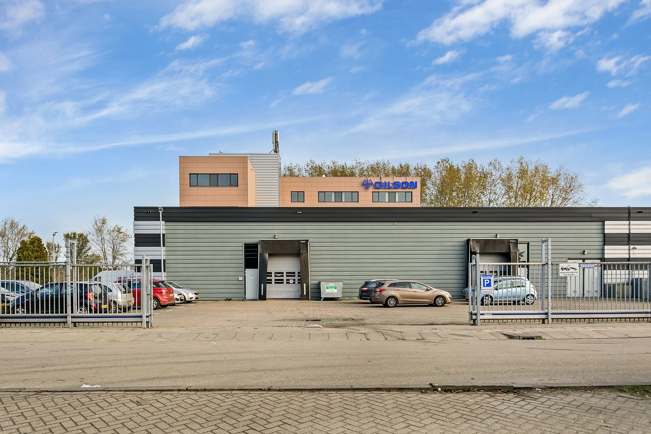 Bedrijfsgebouw van Gilson aan de Laan van ’s-Gravenmade met parkeerplaatsen en laadperrons op de voorgrond.