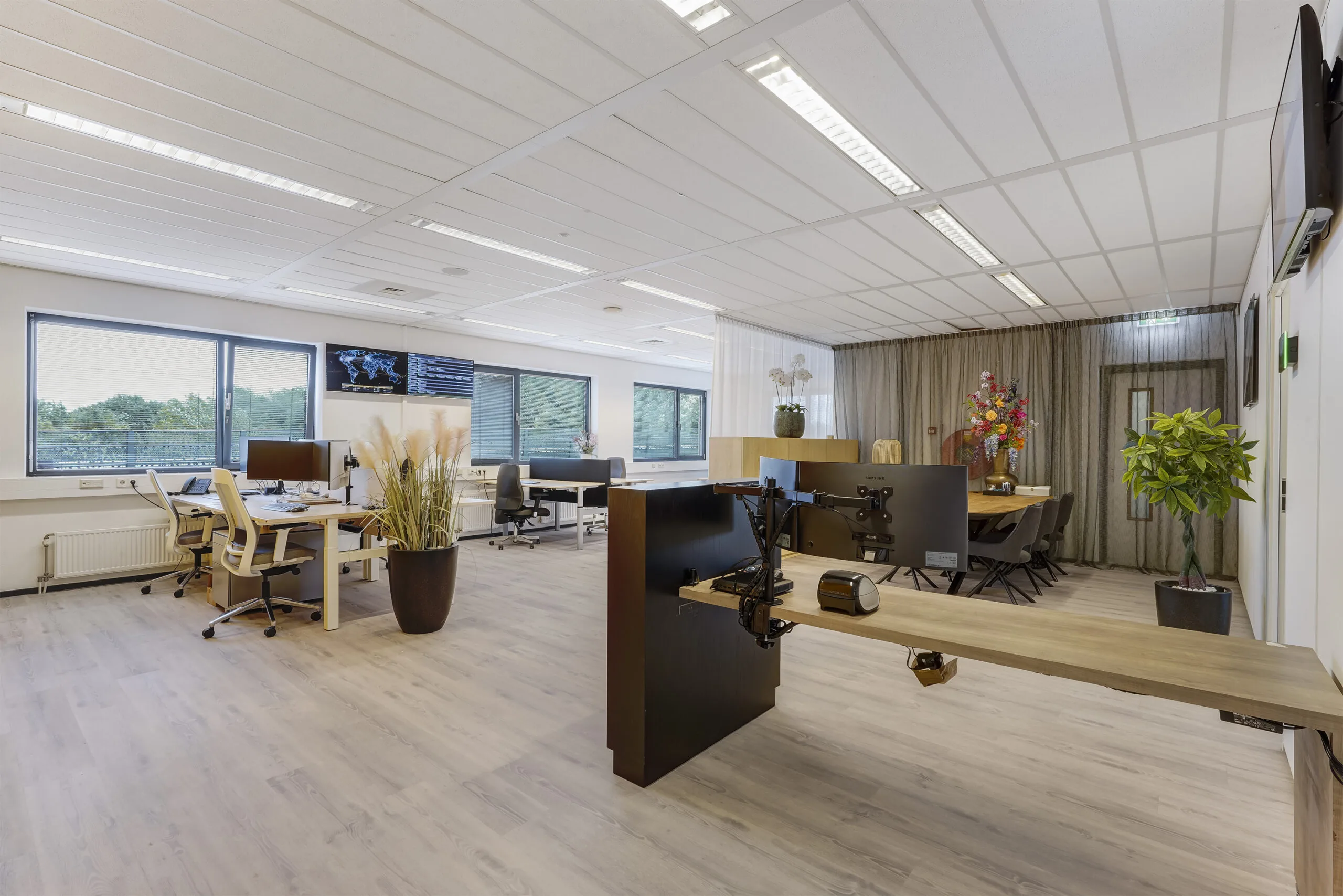 Moderne, lichte kantoorruimte aan de Laan van ’s-Gravenmade met meerdere werkplekken, planten en een vergadertafel.