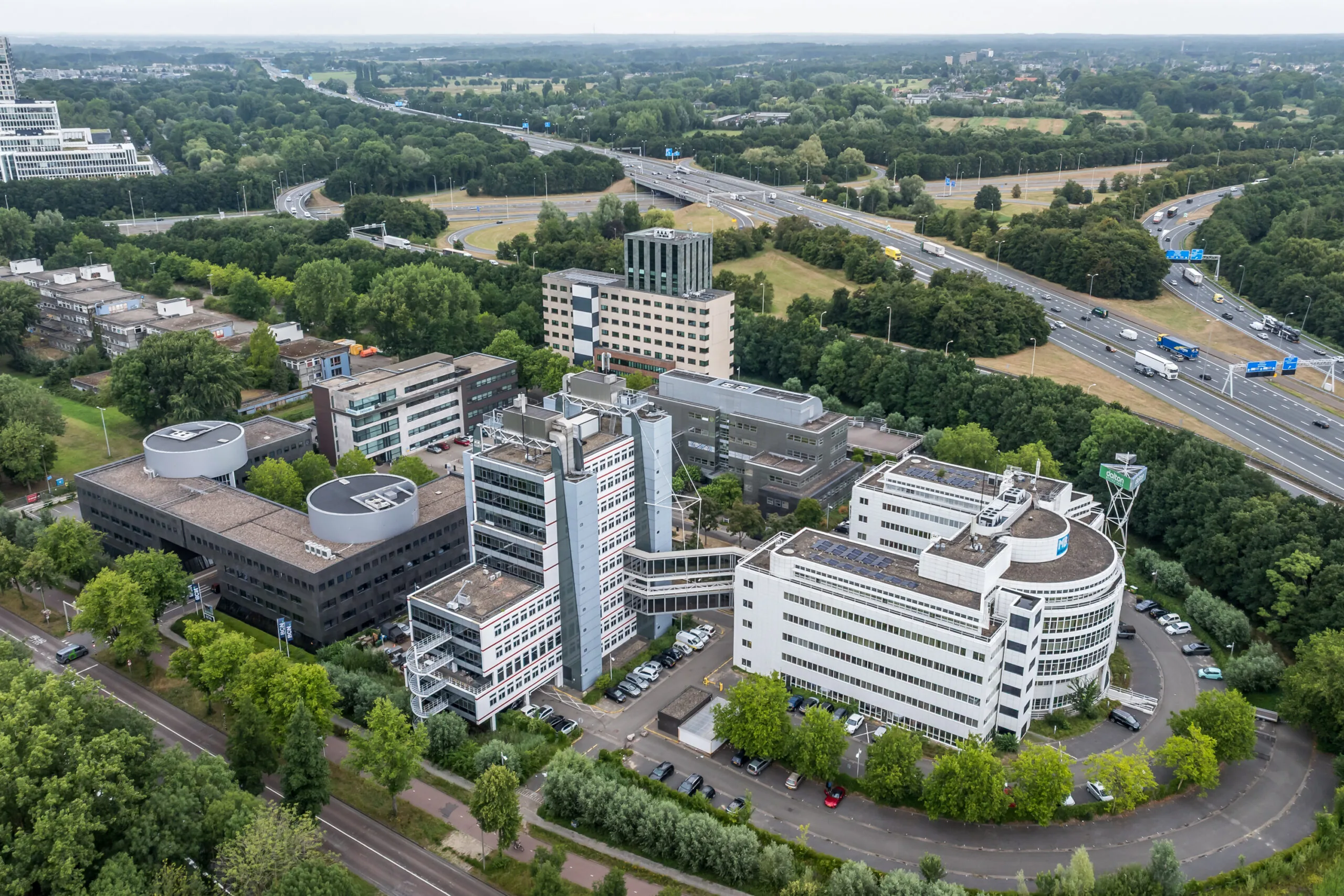 Luchtfoto van het kantoorgebouw aan de Daltonlaan in Utrecht, omringd door groen en nabijgelegen snelwegen.