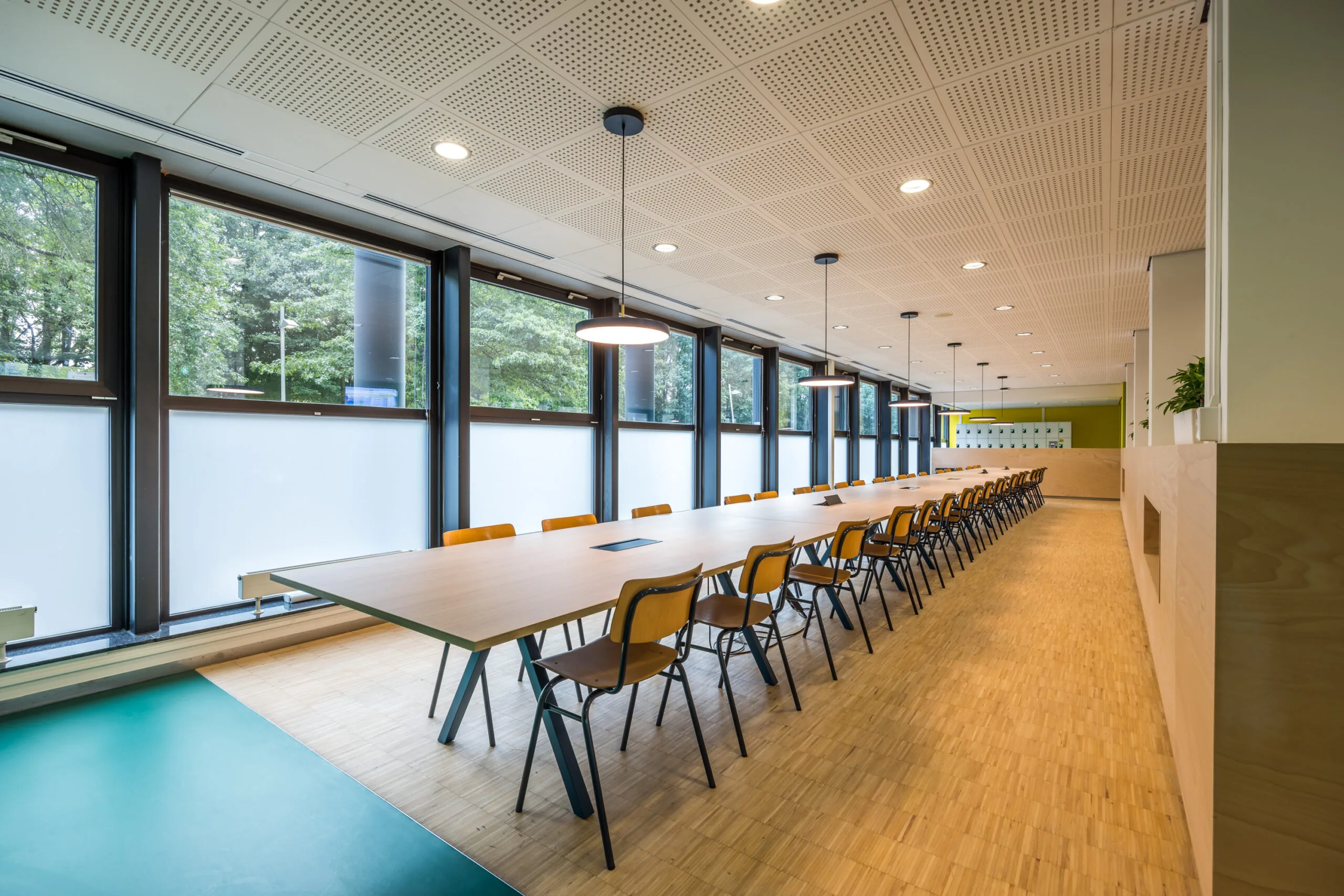 Moderne vergaderruimte aan de Daltonlaan met lange tafel, houten stoelen en grote ramen met uitzicht op groen.