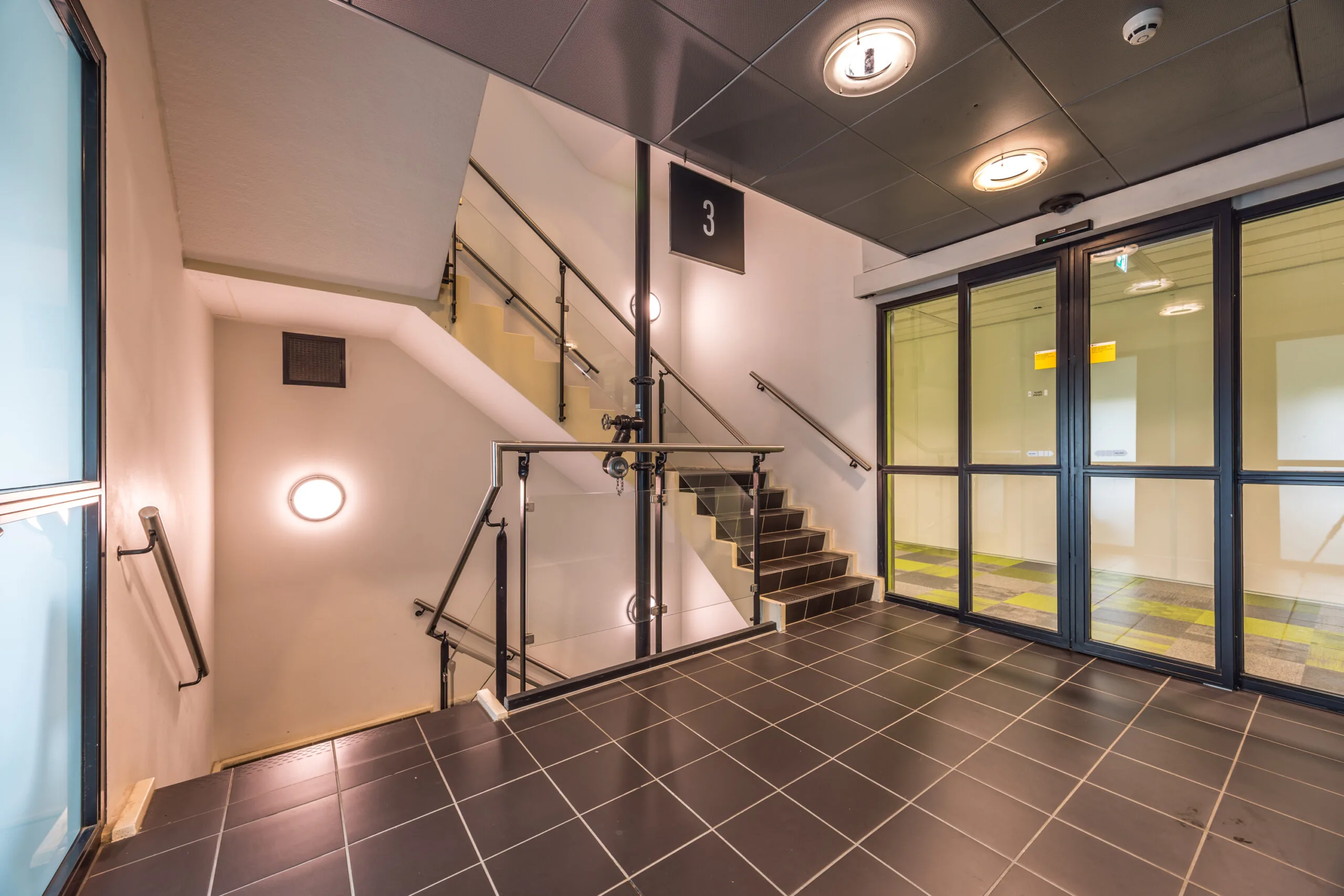 Trappenhuis met glazen deuren en bord dat verdieping 3 aanduidt in kantoorgebouw aan de Daltonlaan.
