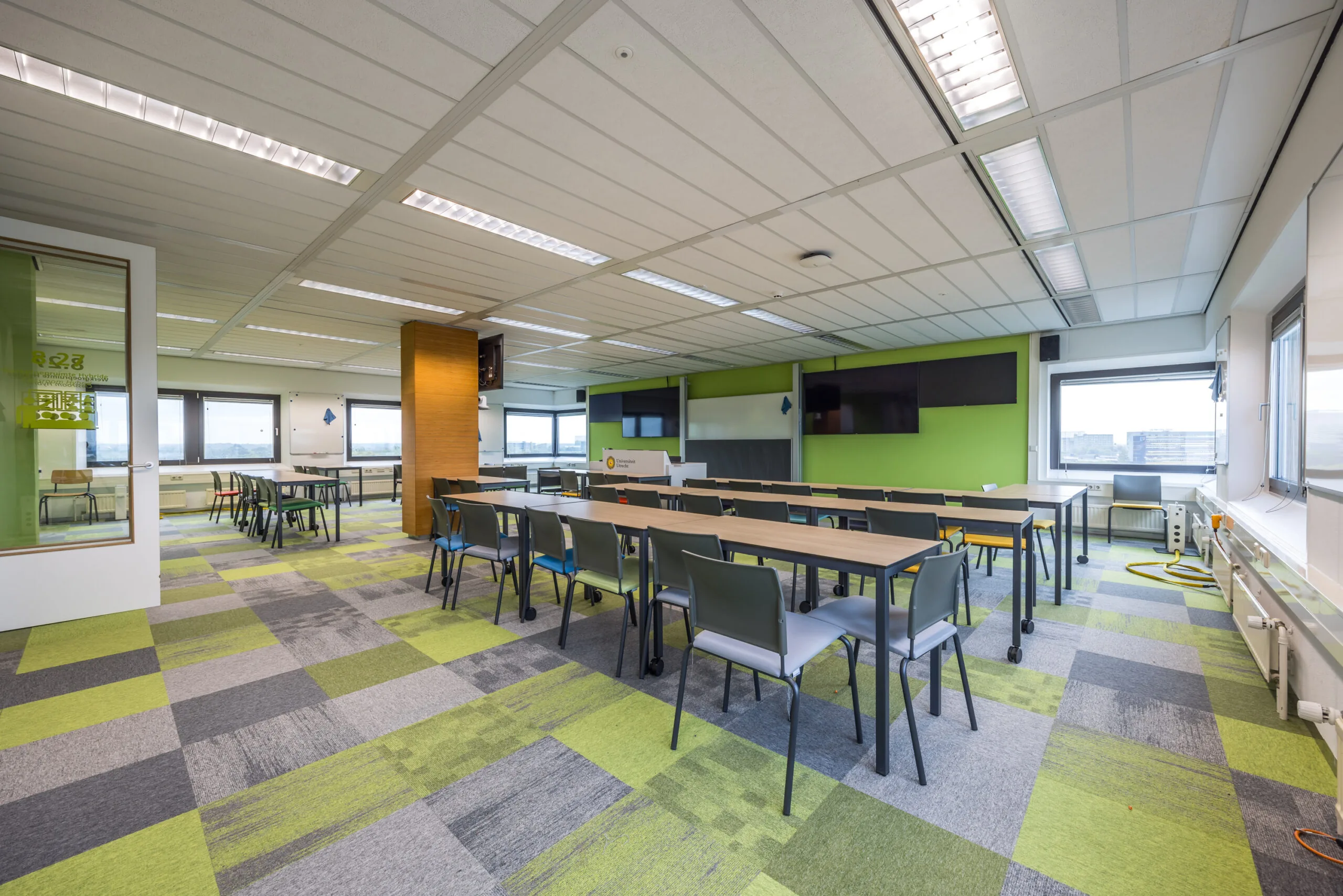 Modern ingerichte vergaderruimte aan de Daltonlaan met kleurrijk tapijt, lange tafels en presentatieapparatuur.