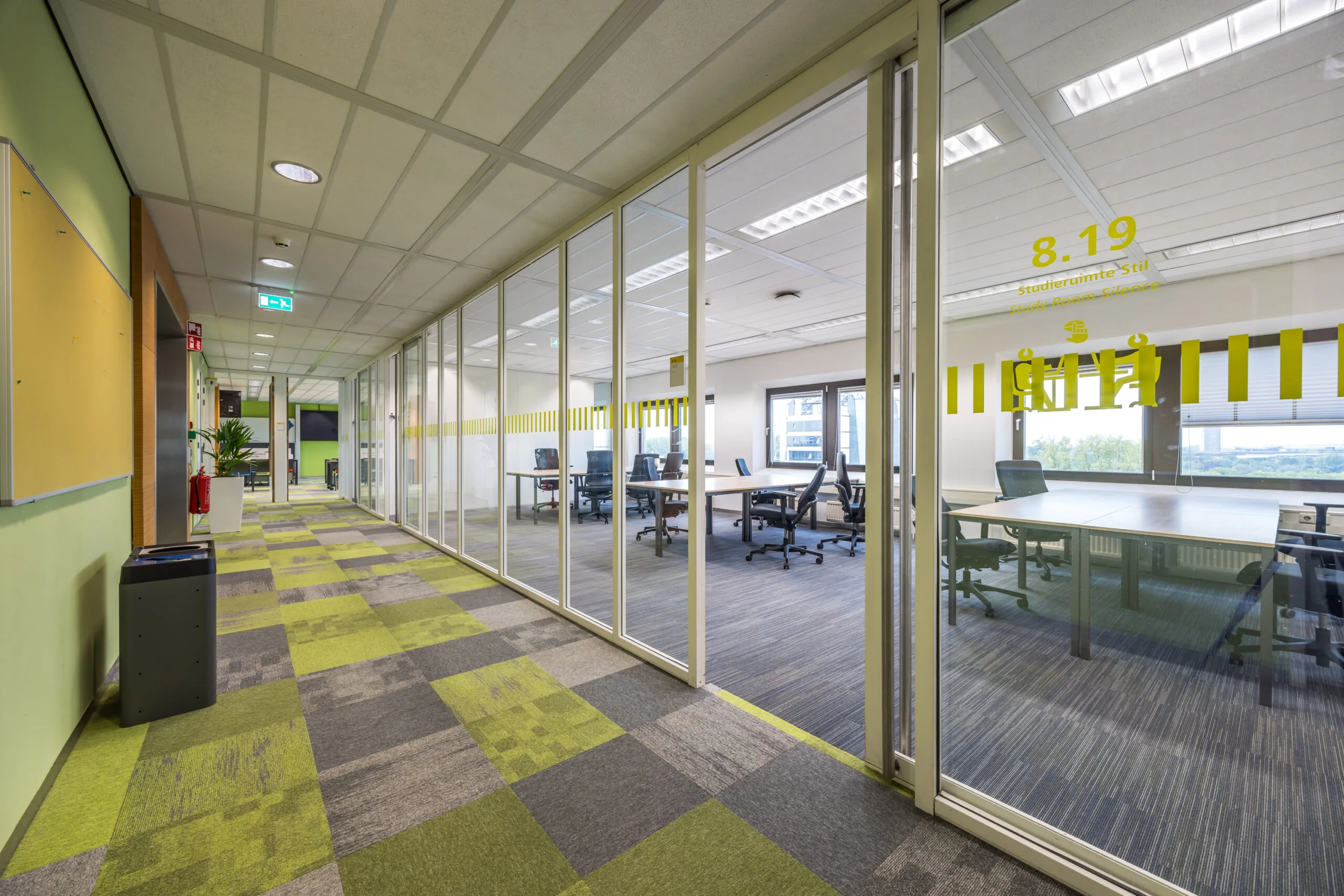 Moderne gang met glazen wanden die uitkijken op studieruimte 8.19 in kantoorgebouw aan de Daltonlaan.