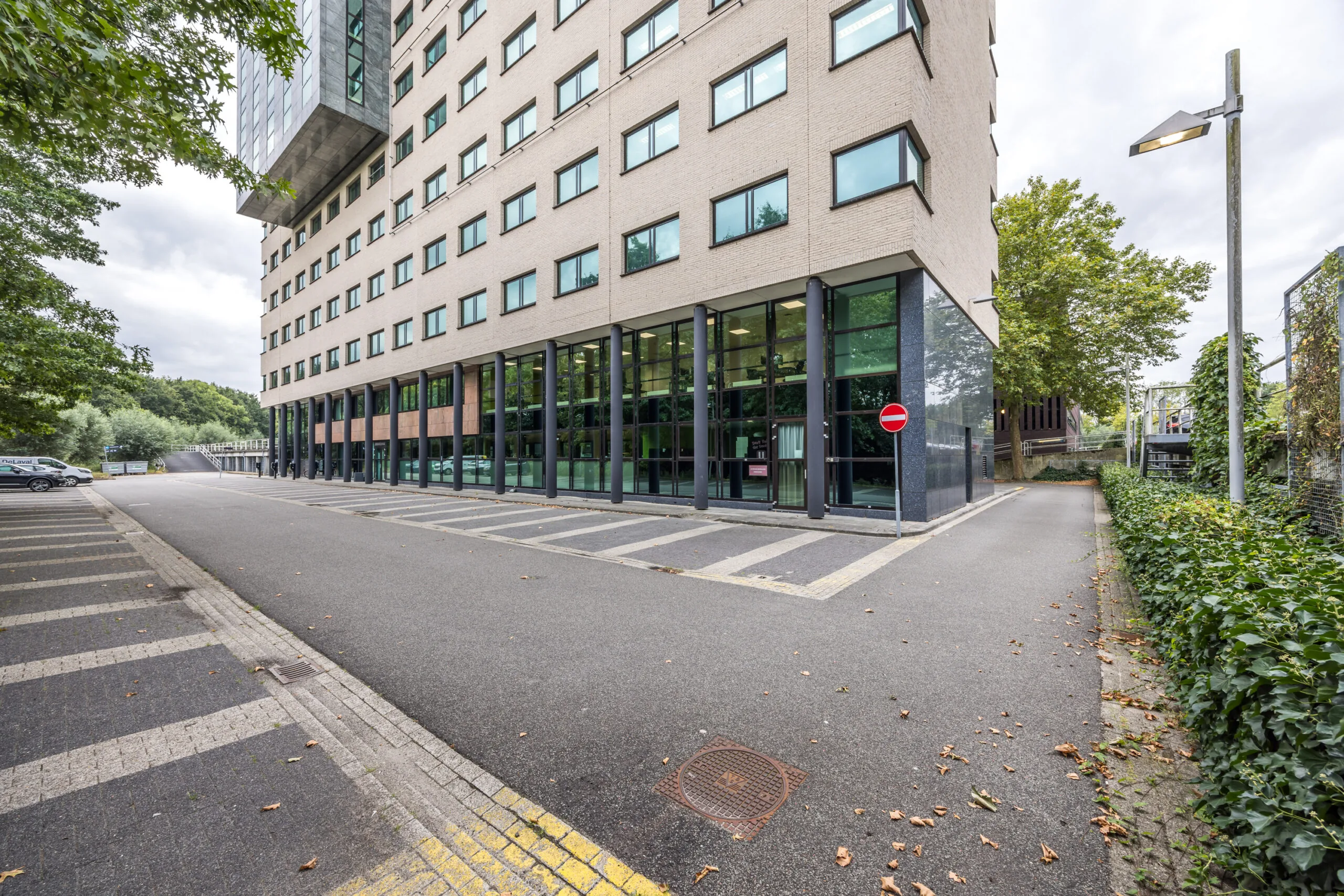 Kantoorgebouw aan de Daltonlaan met glazen gevel en parkeerstrook op de voorgrond.