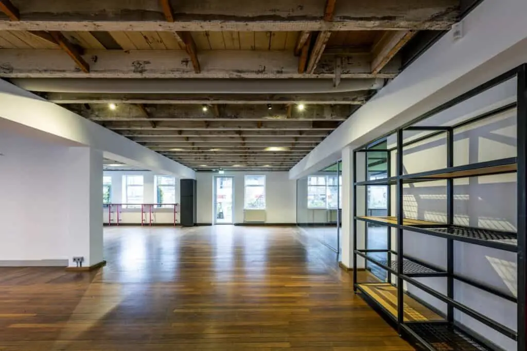 Een industriële, open kantoorruimte aan de De Ruijterkade met houten vloer, zichtbaar balkenplafond en grote ramen.