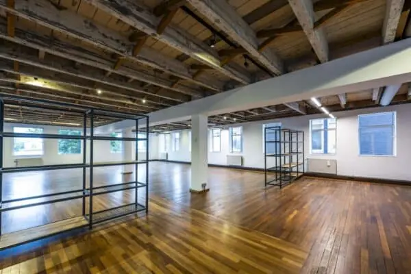 Ruime, lichte kantoorruimte aan de De Ruijterkade met houten vloer, zichtbare houten balken en metalen vakkenkasten.
