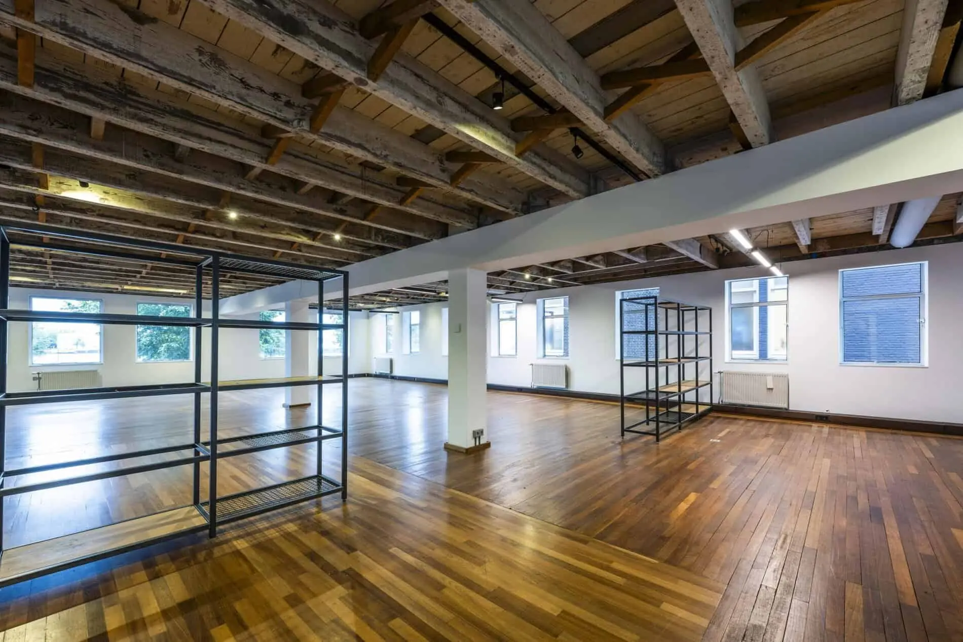 Ruime, lichte kantoorruimte aan de De Ruijterkade met houten vloer, zichtbare houten balken en metalen vakkenkasten.