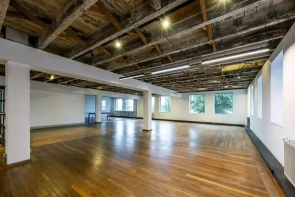 Ruime, lichte kantoor- of werkruimte aan de De Ruijterkade met houten vloer, industriële plafondbalken en grote ramen.