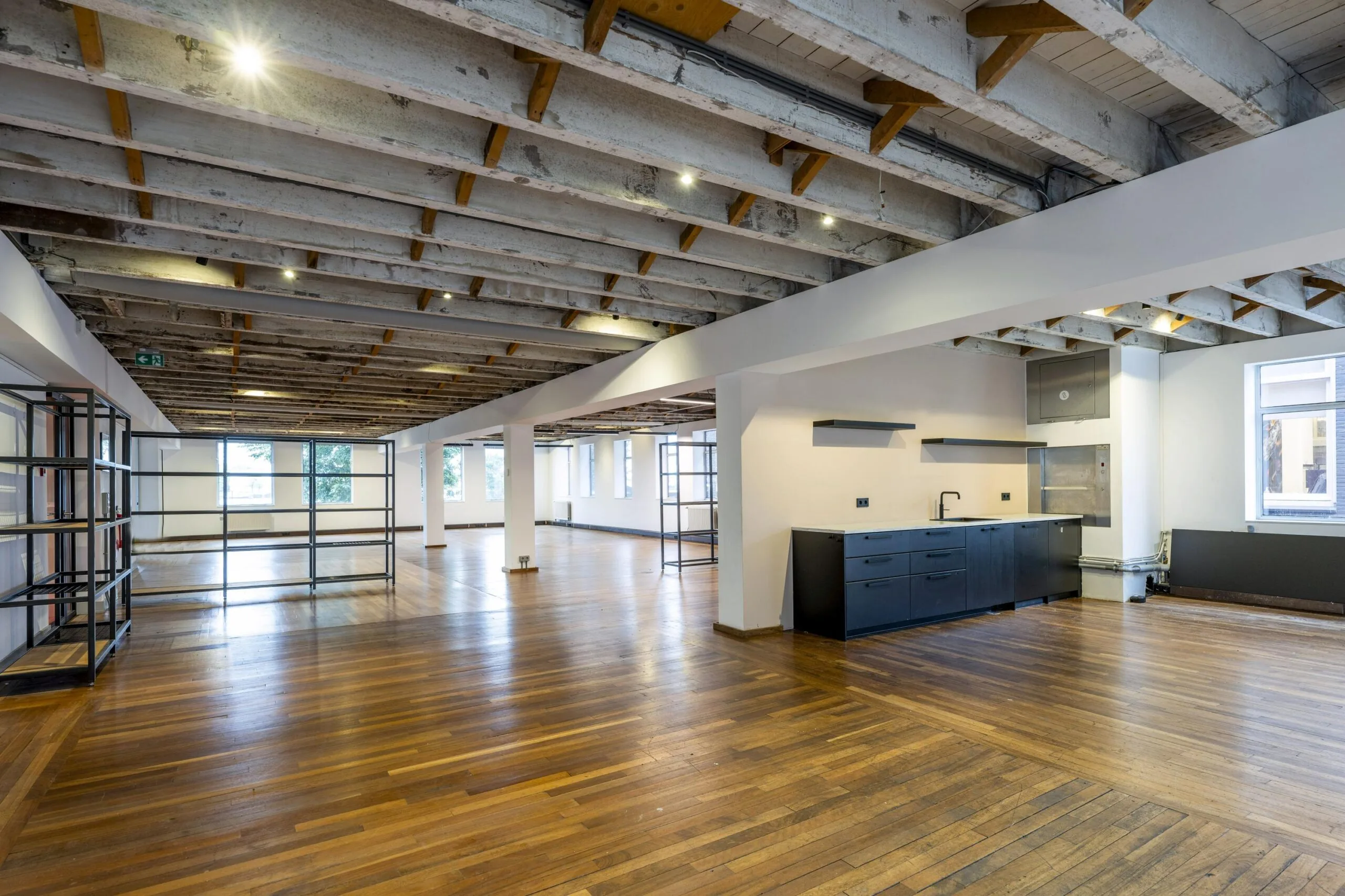 Licht en ruim industrieel kantoorinterieur aan de De Ruijterkade met houten vloer, open plafond en moderne kitchenette.