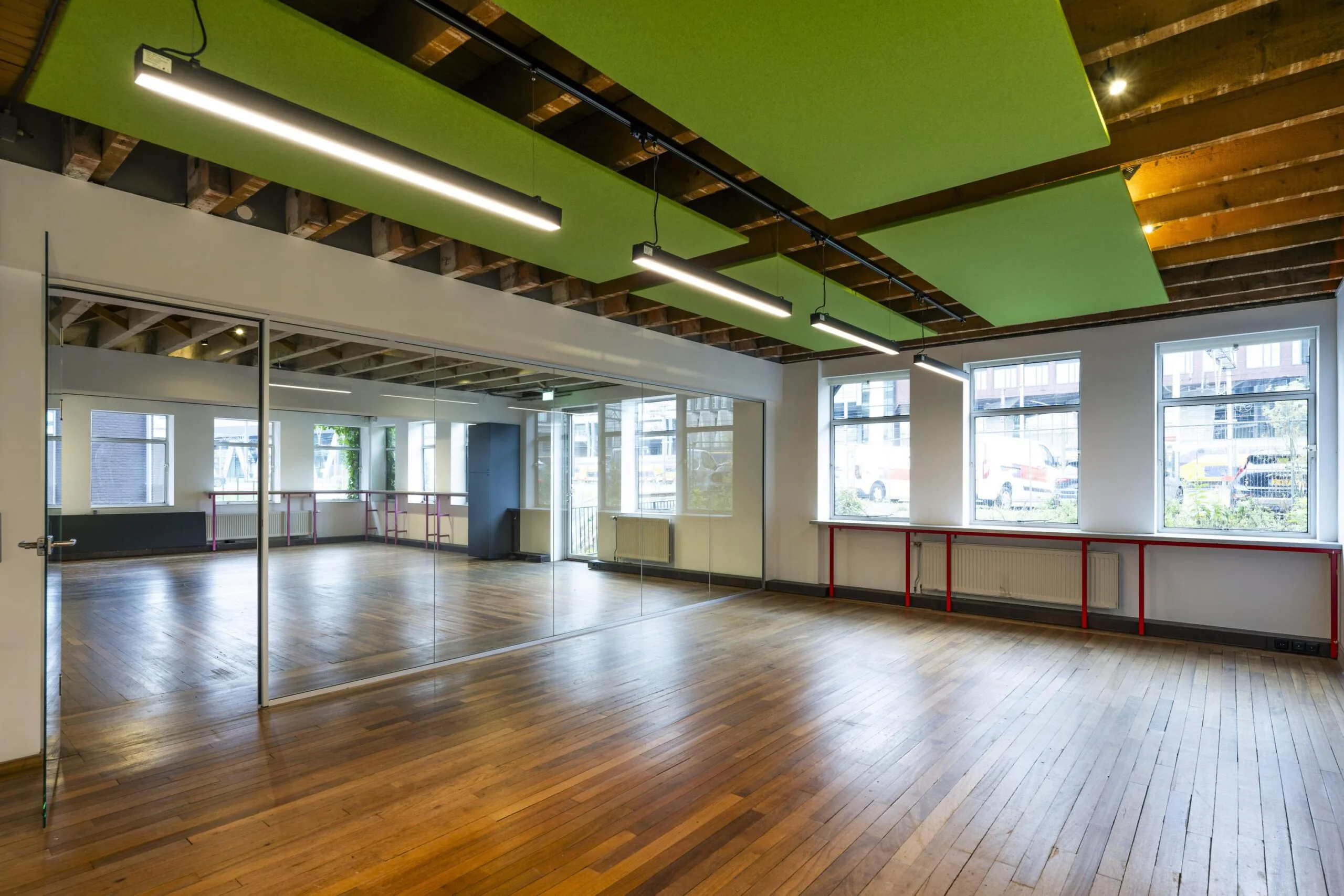 Lichte, moderne ruimte aan de De Ruijterkade met houten vloer, spiegelwand en zichtbare plafondconstructie.