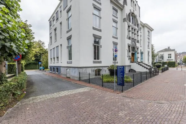 Wit kantoorgebouw aan de Driebergseweg met het bord "Kosmos" bij de ingang en een trap aan de voorzijde.