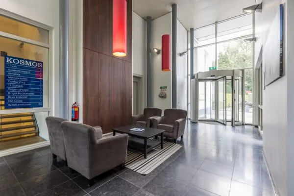 Entreehal van het kantoorgebouw aan de Driebergseweg met zithoek, bedrijfsnaambord en draaideur.