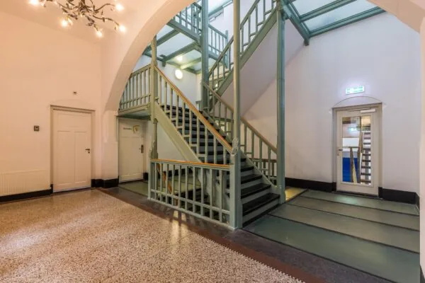 Trappenzaal met groen geschilderde houten trap en glazen plafond in een pand aan de Driebergseweg.