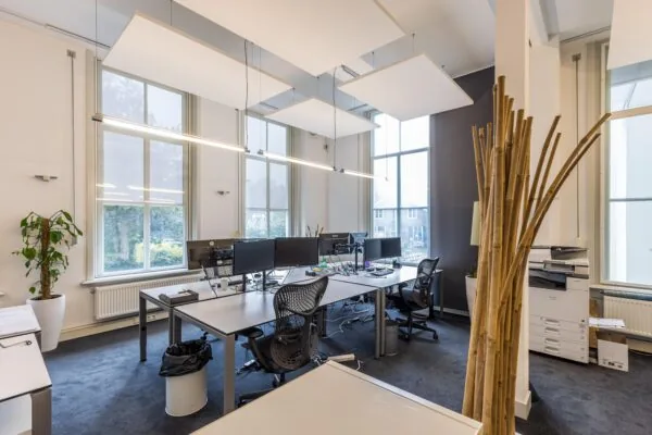 Modern ingericht kantoor aan de Driebergseweg met bureaus, kantoorstoelen, computers en grote ramen.