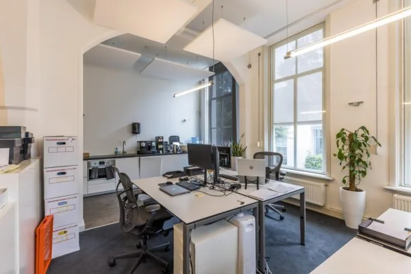 Modern ingericht kantoor aan de Driebergseweg met werkplekken, grote ramen en een kitchenette.