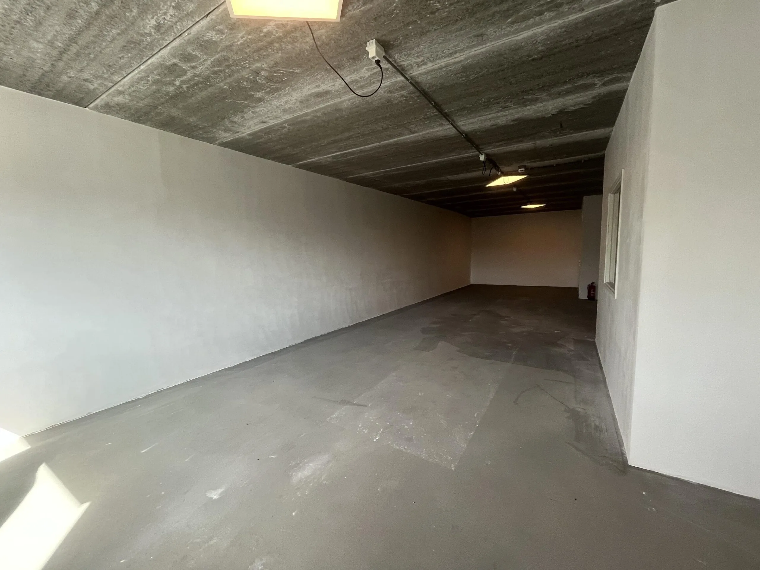 Leeg, betonnen bedrijfspand of garage aan de Broekdijk West met gestucte muren en een onafgewerkte vloer.