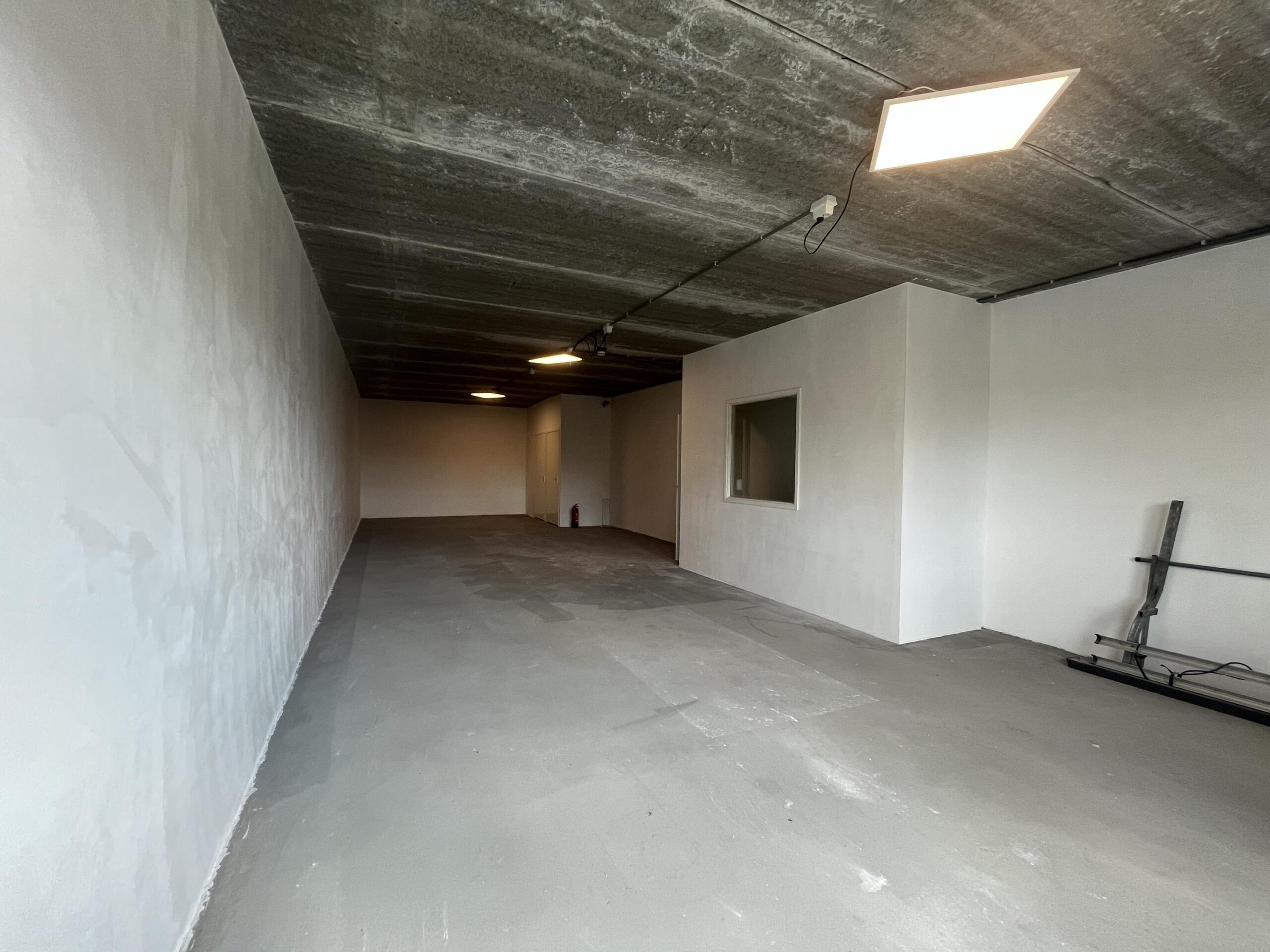 Een lege, kale ruimte met betonvloer en witte muren op Broekdijk West.