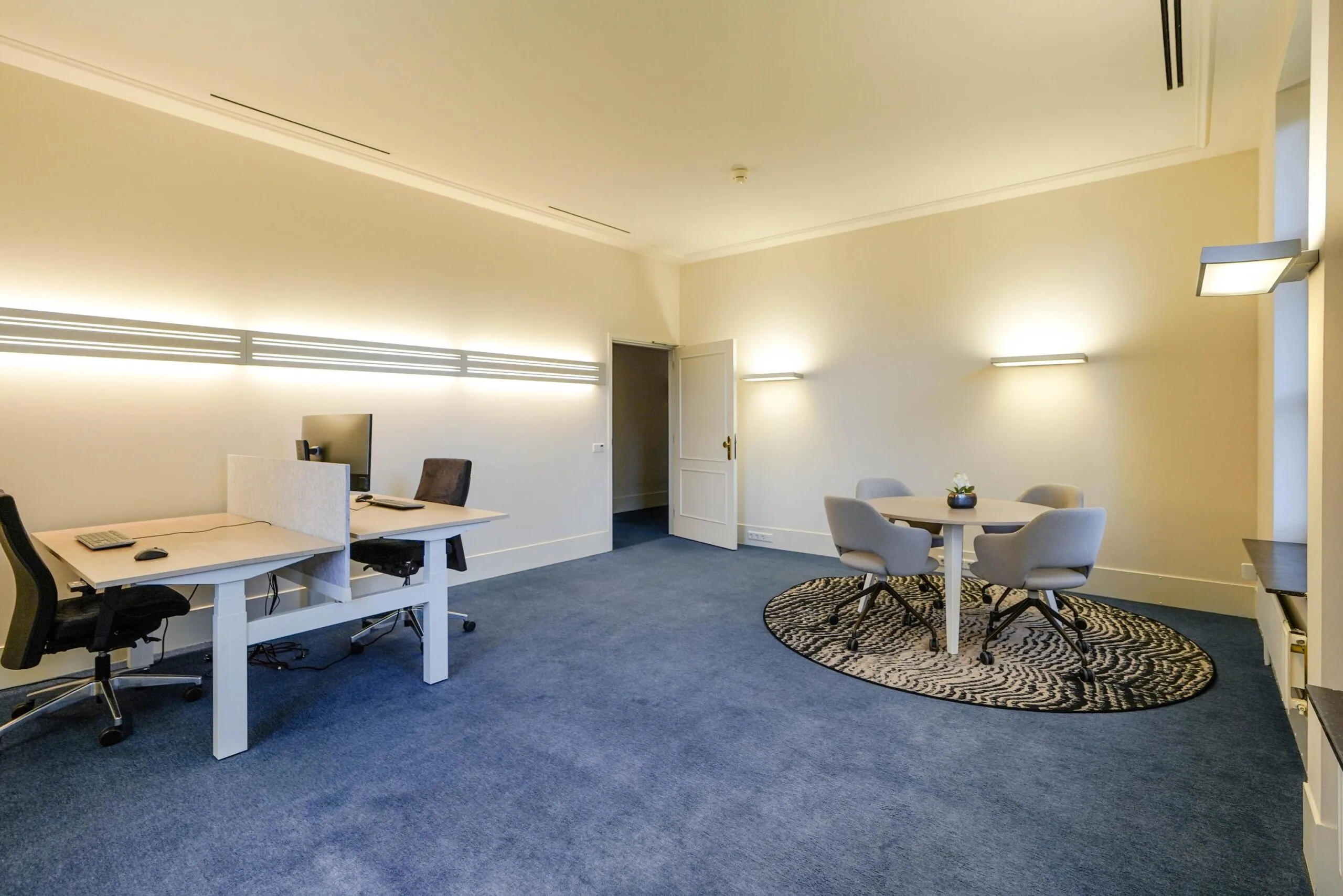 Modern ingerichte kantoorruimte aan de Utrechtseweg met twee werkplekken en een ronde vergadertafel.
