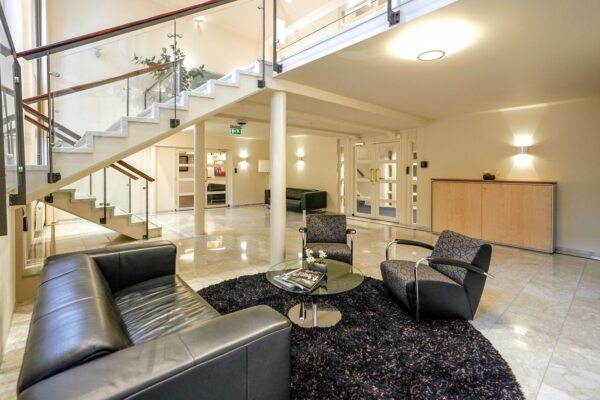 Moderne ontvangstruimte aan de Utrechtseweg met glazen trap, zitgedeelte en marmeren vloer.