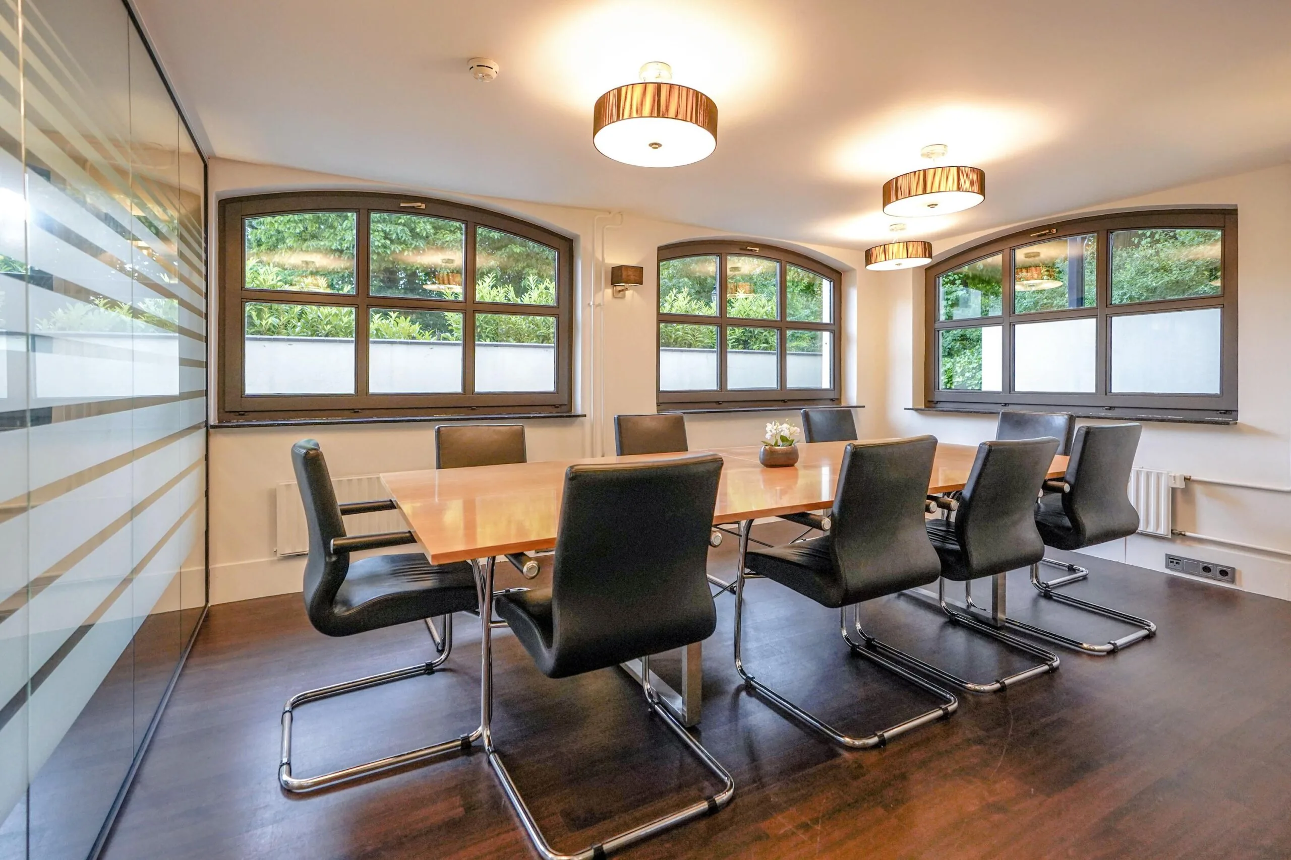 Moderne vergaderruimte aan de Utrechtseweg met houten tafel, zwarte stoelen en grote ramen met uitzicht op groen.