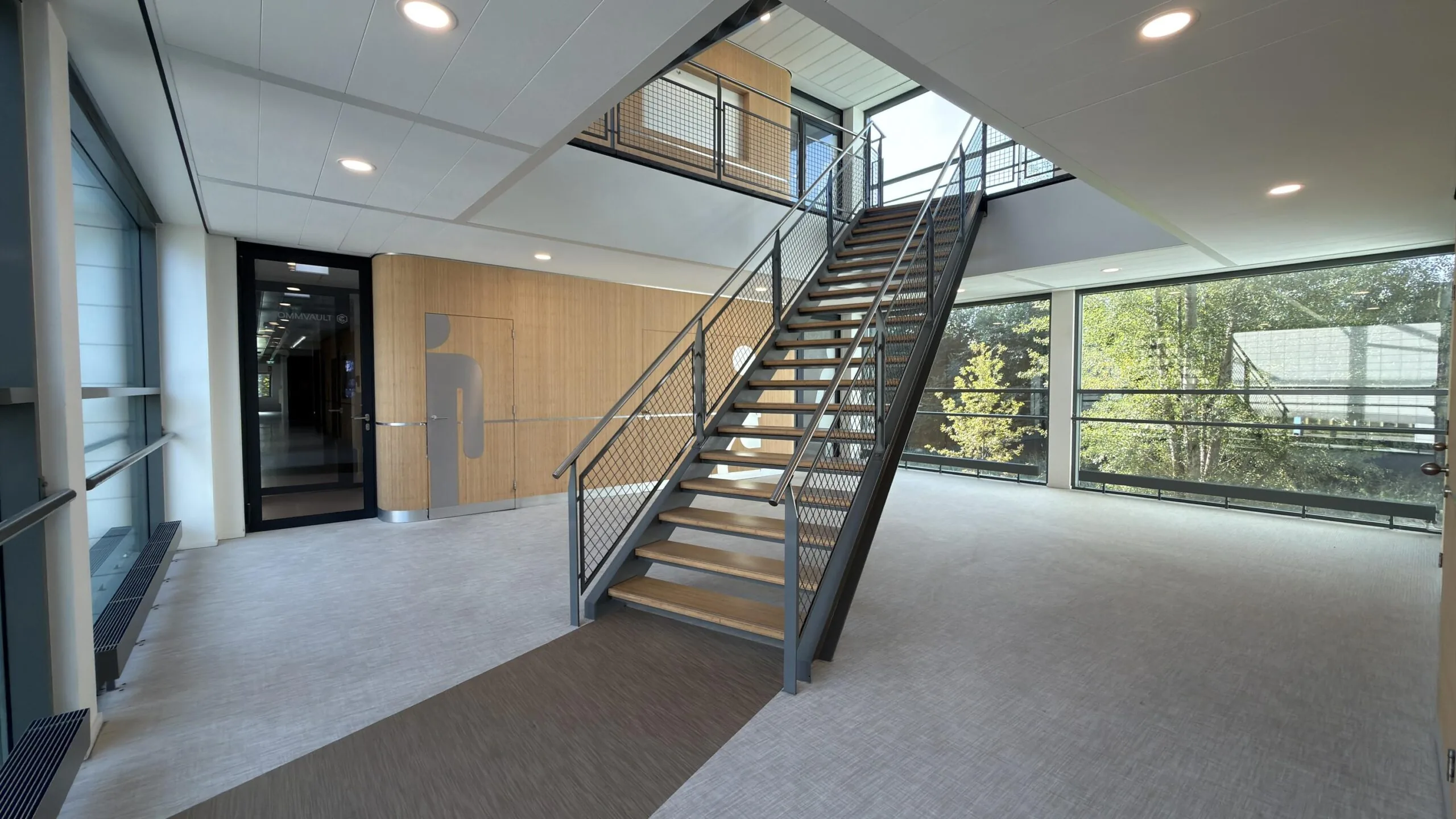 Moderne kantoorruimte aan de Papendorpseweg met een centrale houten trap, glazen wanden en natuurlijke lichtinval.