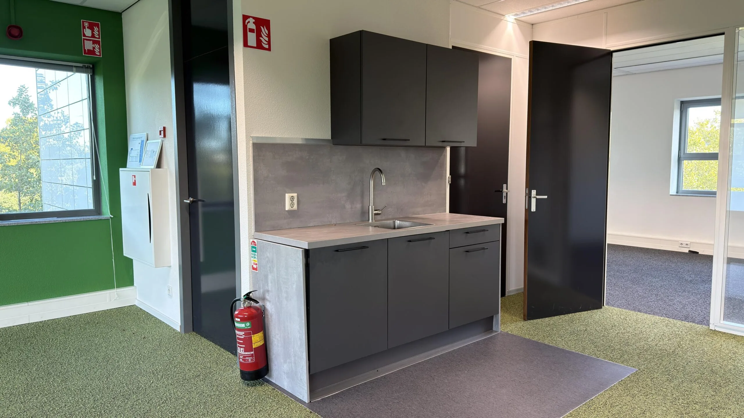 Kleine pantry met zwarte keukenkastjes in een modern kantoor aan de Papendorpseweg.