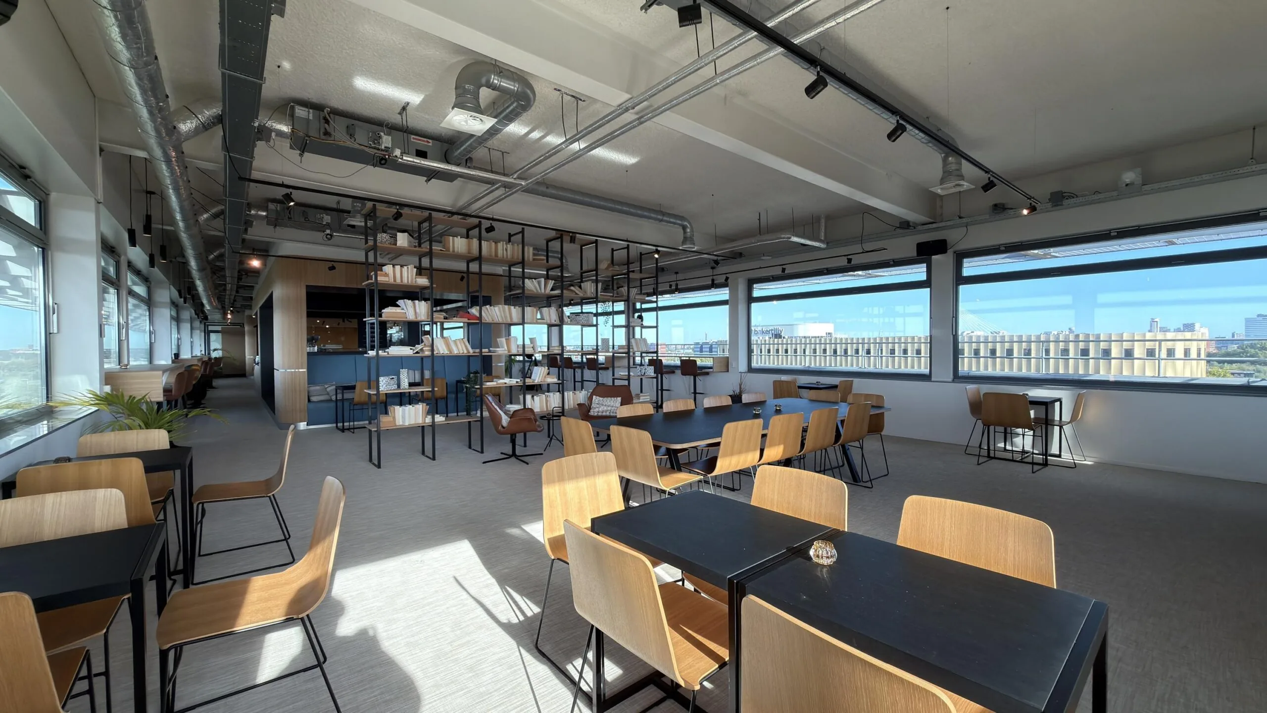 Moderne, lichtovergoten kantoorruimte aan de Papendorpseweg met open zitgedeeltes, boekenkasten en uitzicht op de stad.