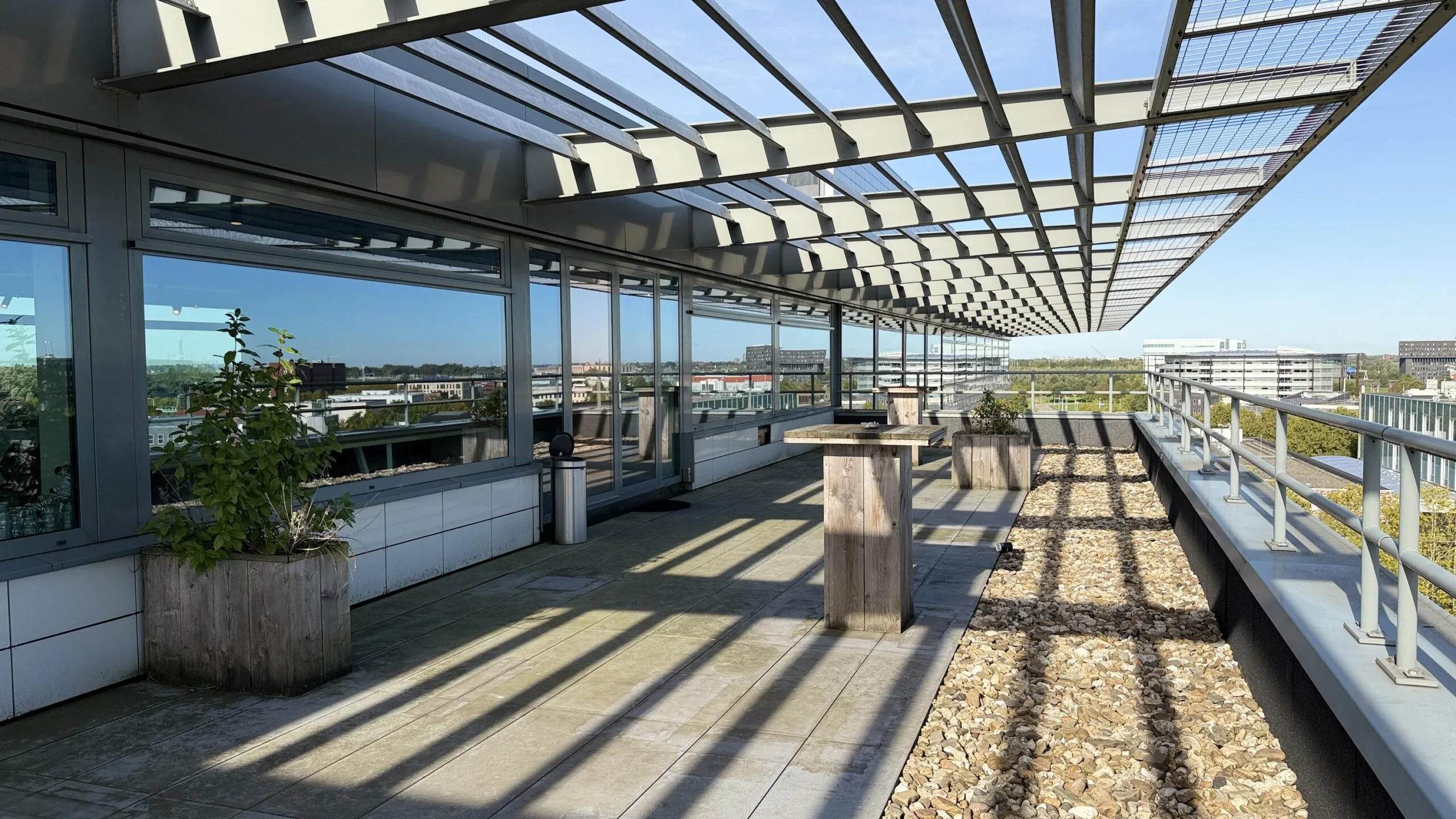 Zonnig dakterras met plantenbakken en zitgelegenheid aan de Papendorpseweg met uitzicht op omliggende kantoorgebouwen.