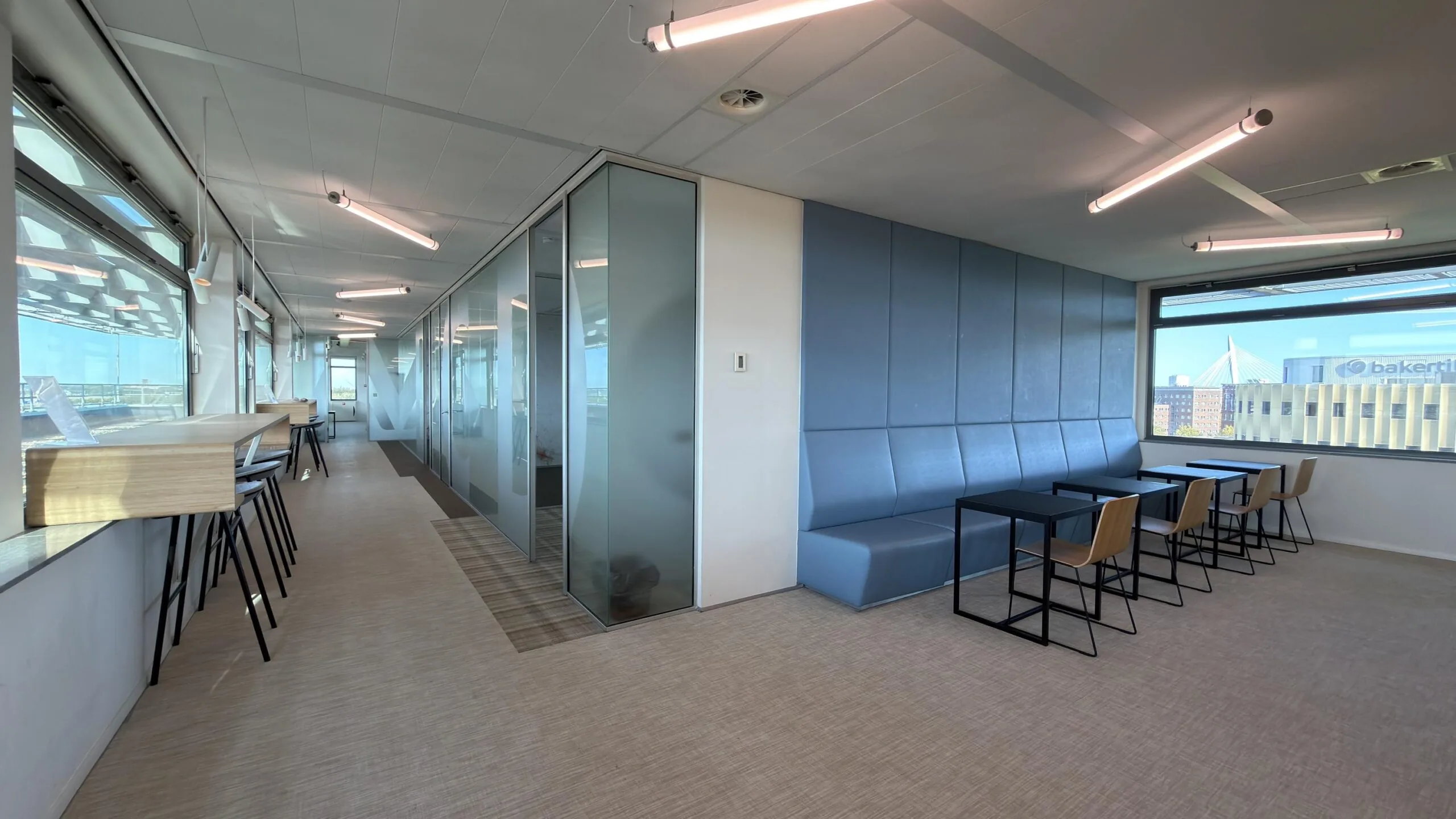 Moderne kantoorruimte aan de Papendorpseweg met glazen vergaderruimtes, zitgedeelte en uitzicht op de stad.