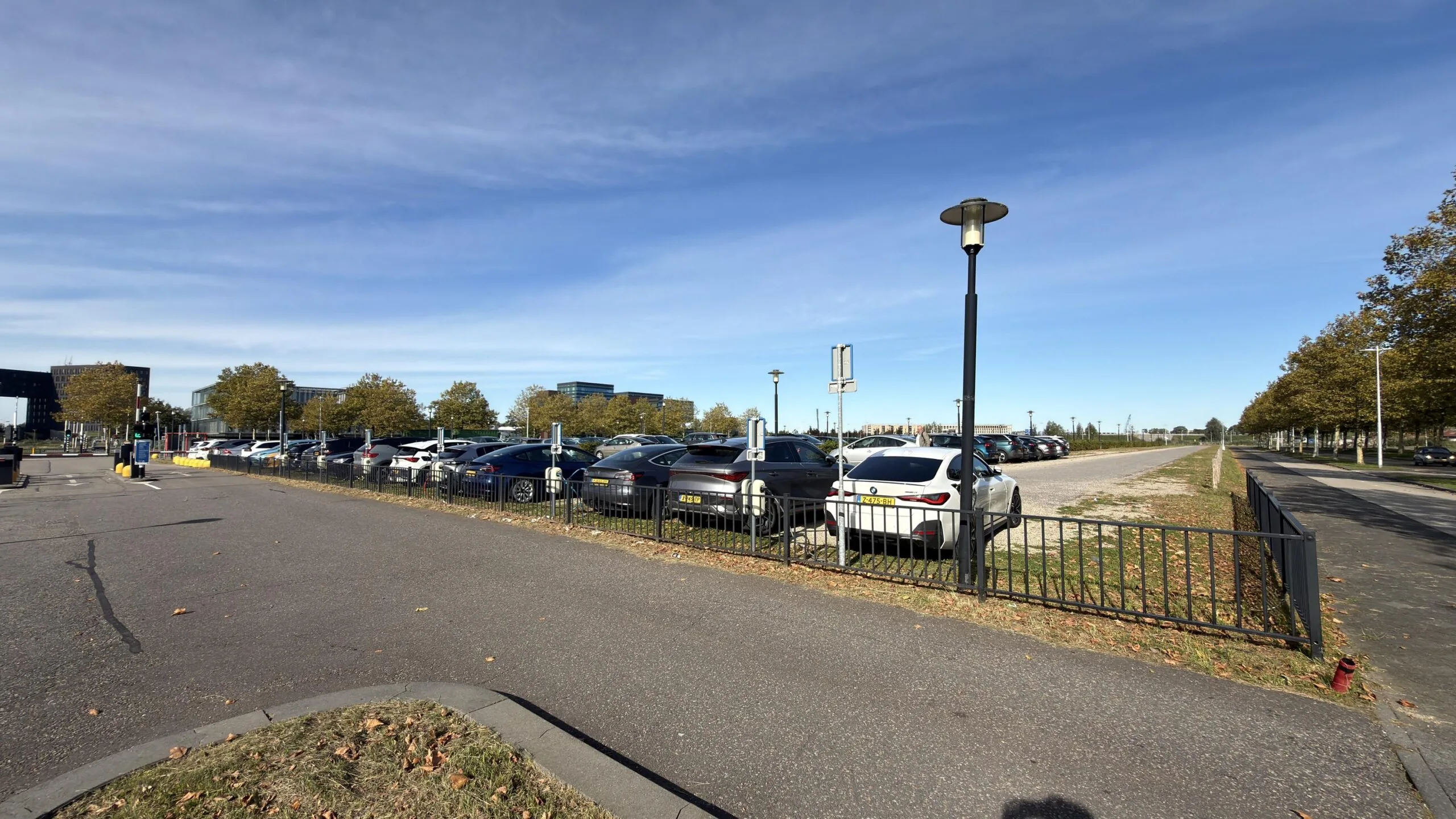 Parkeerterrein aan de Papendorpseweg met geparkeerde auto's en omringende kantoorgebouwen op een zonnige dag.