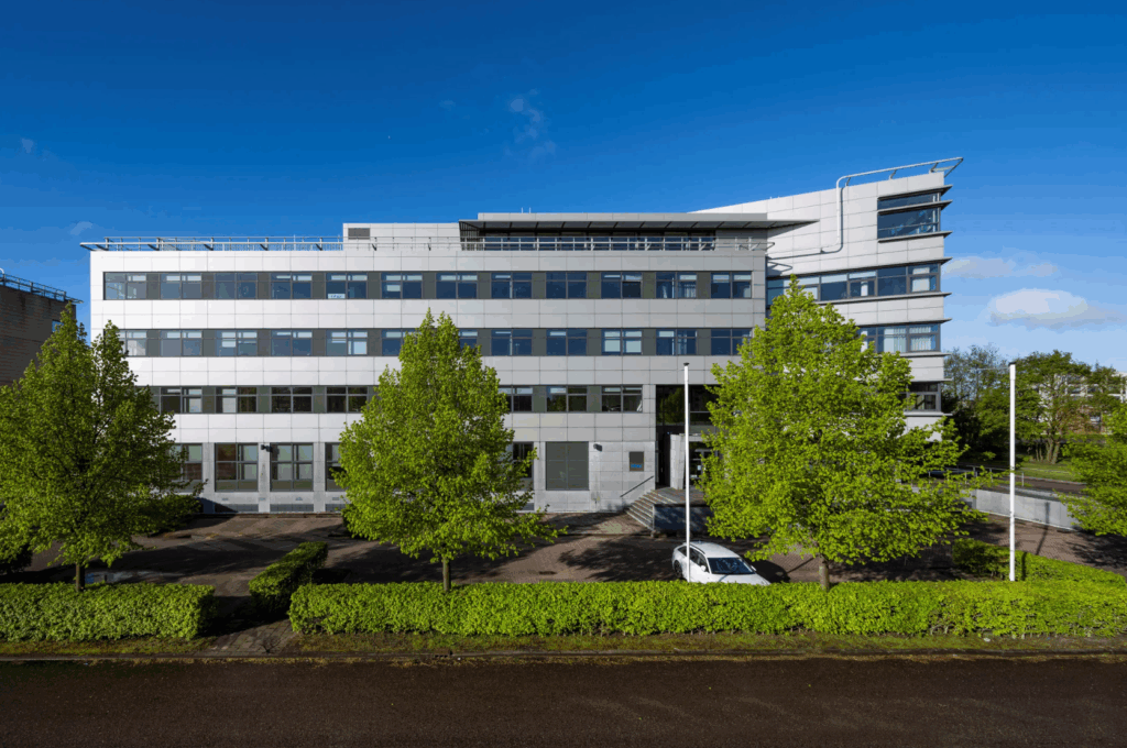 Modern kantoorgebouw aan de Boeingavenue met glazen gevel en omliggende groenvoorziening.