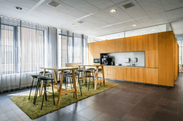 Moderne pantry met houten keukenkasten, hoge tafels, barkrukken en grote ramen met lichte gordijnen in een kantoor aan de Boeing Avenue.