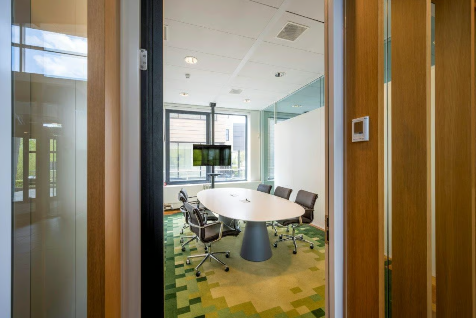 Vergaderruimte op Boeing Avenue met ovale tafel, zes stoelen en een flatscreen aan het raam.